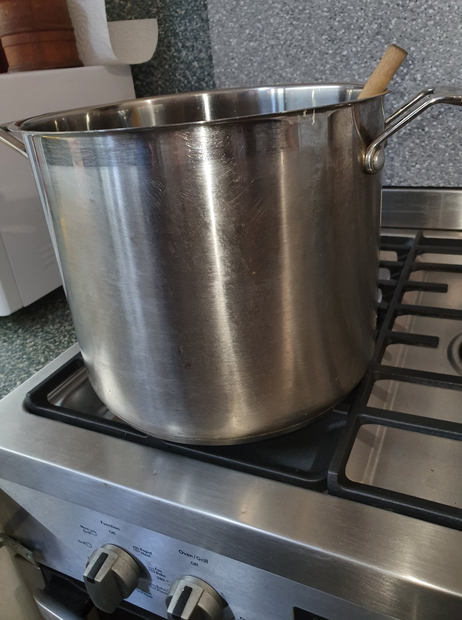 Image of a large stainless steel pot with a wooden utensil sticking out the top.